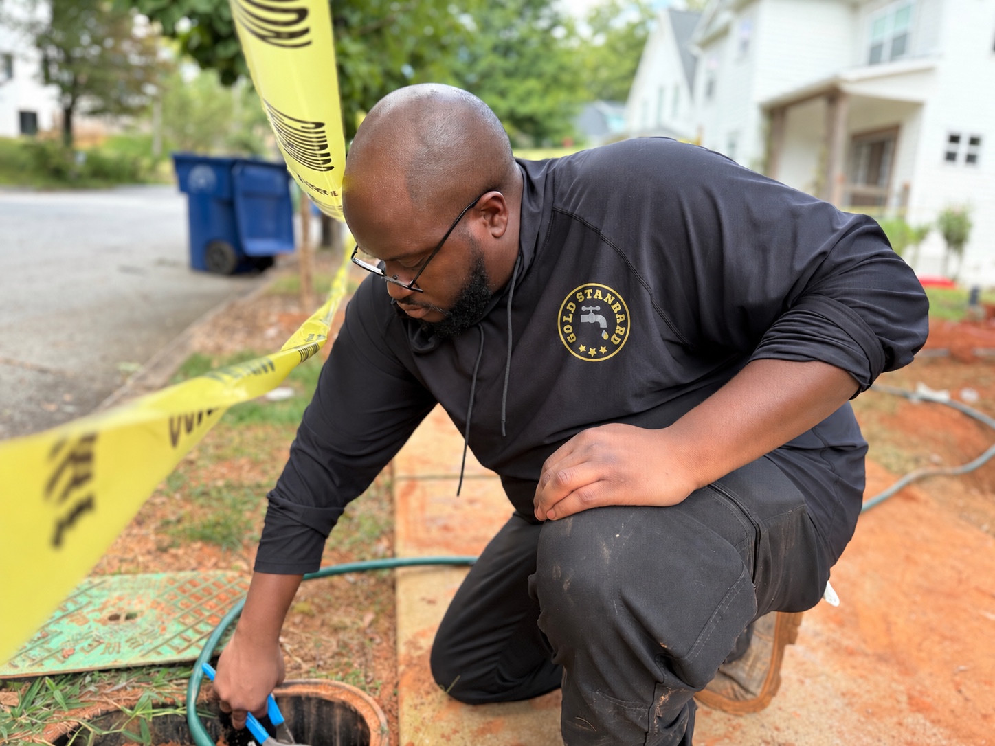 Gold Standard Plumbing technician working beside a water-meter box