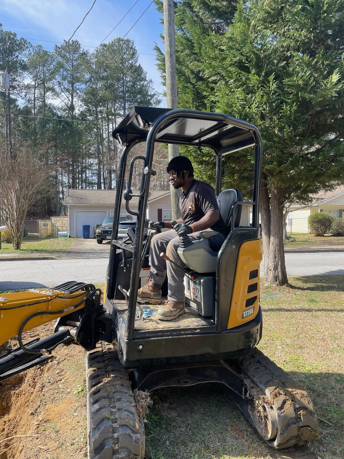 Worker seated at the controls of a yellow mini-excavator