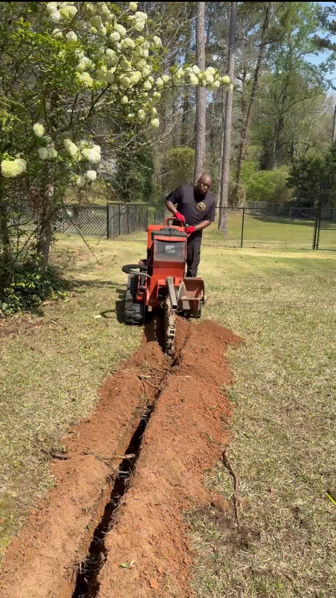 Worker operating a trencher along a residential lawn