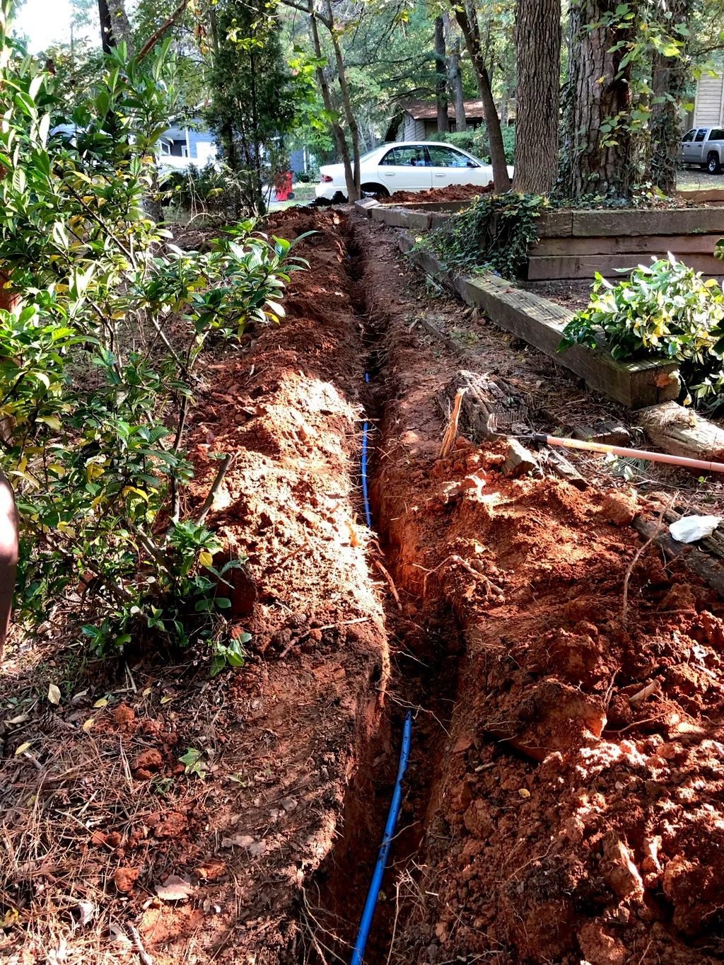 Blue water line in an open trench through a yard